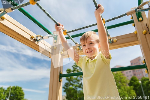 Image of happy little boy climbing on children playground