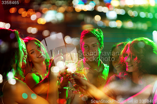 Image of smiling friends with glasses of champagne in club