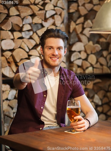 Image of happy man with beer showing thumbs up at bar