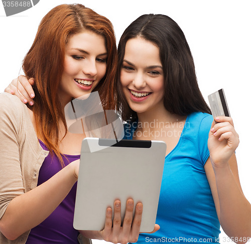 Image of two smiling girls with tablet pc and credit card