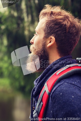 Image of smiling man with beard and backpack hiking