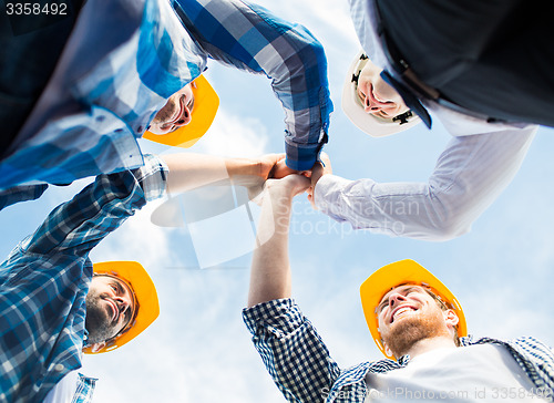 Image of close up of builders in hardhats making high five