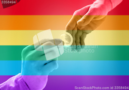 Image of close up of male gay couple hands giving condom