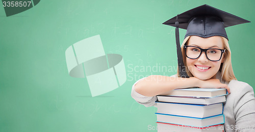 Image of student in trencher cap with books over green