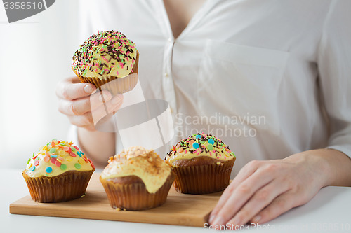 Image of close up of woman with glazed cupcakes or muffins