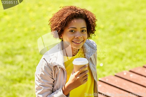 Image of smiling african woman drinking coffee outdoors 