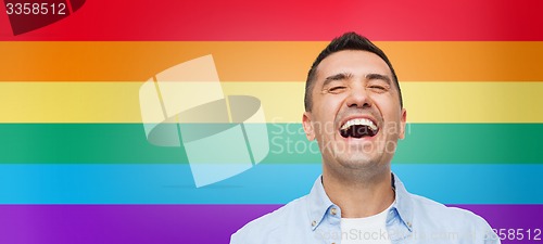 Image of laughing man over rainbow flag stripes background