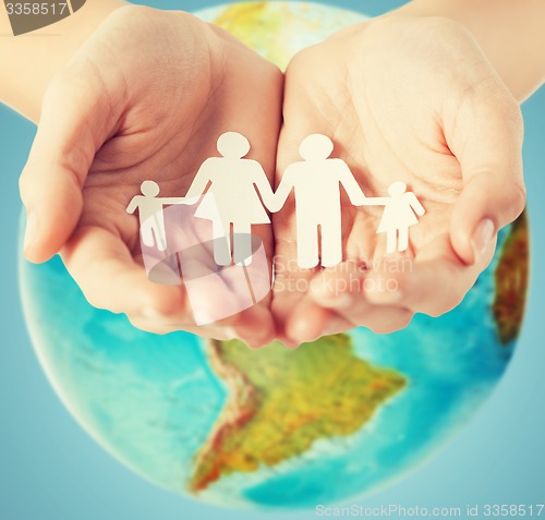 Image of human hands holding paper family over earth globe