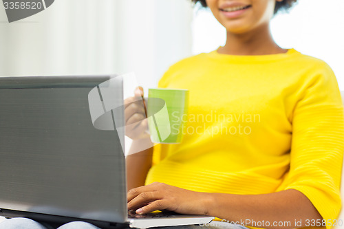 Image of happy african american woman with laptop at home