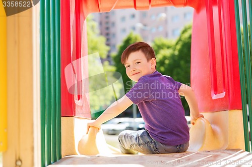 Image of happy little boy on slide at children playground