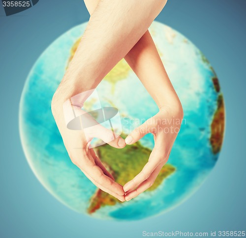 Image of human hands showing heart shape over earth globe