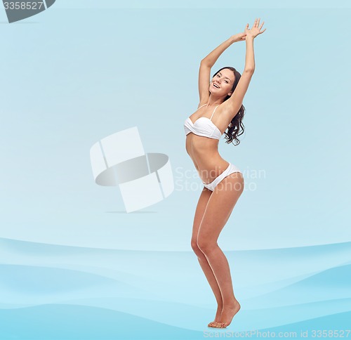 Image of happy young woman in white bikini swimsuit dancing