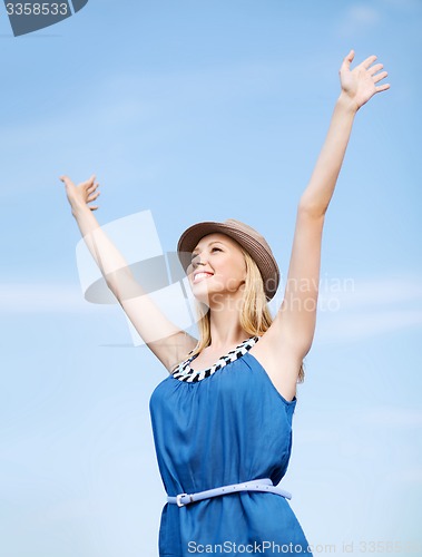 Image of girl with hands up on the beach