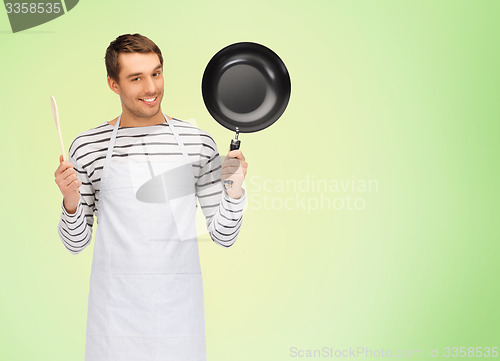 Image of happy man or cook in apron with pan and spoon