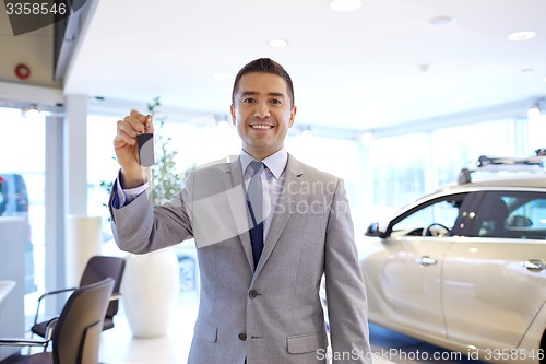 Image of happy man showing key at auto show or car salon