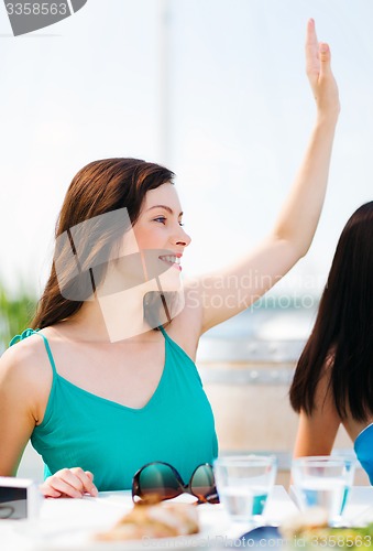 Image of girl waving hand in cafe on the beach