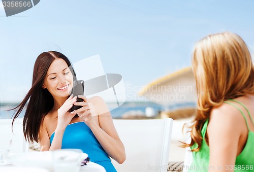 Image of girls taking photo in cafe on the beach