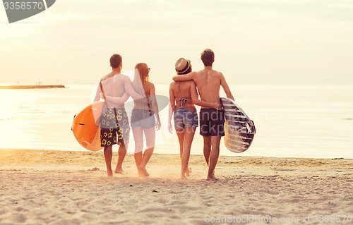 Image of smiling friends in sunglasses with surfs on beach