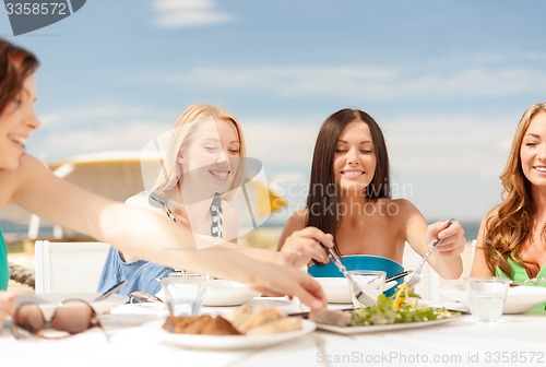 Image of smiling girls in cafe on the beach