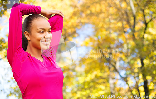 Image of smiling african woman stretching hand outdoors