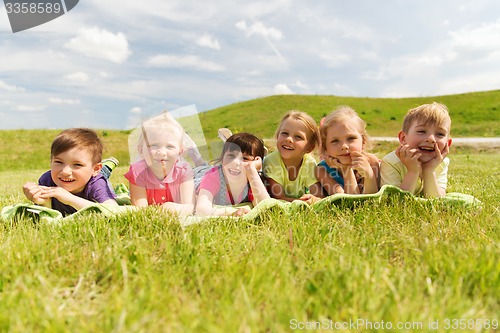 Image of group of kids lying on blanket or cover outdoors