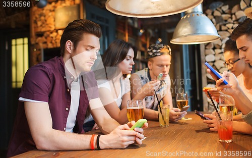 Image of friends with smartphones and drinks at bar