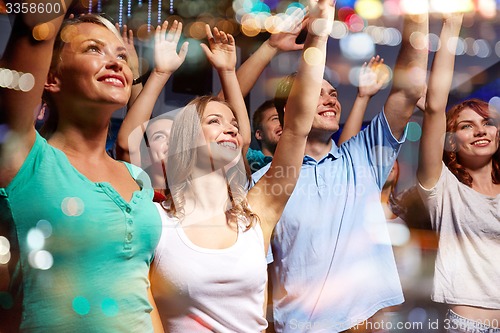 Image of smiling friends at concert in club