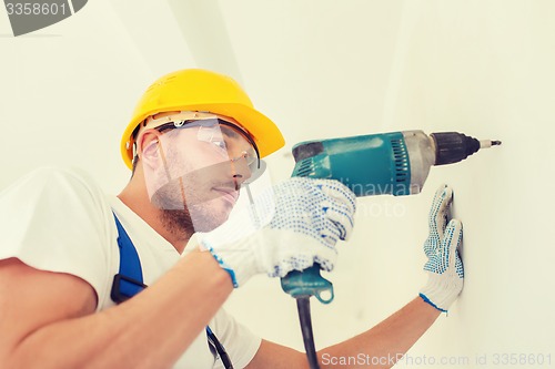 Image of builder in hardhat working with drill indoors