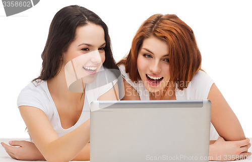 Image of two smiling teenage girsl with laptop computer