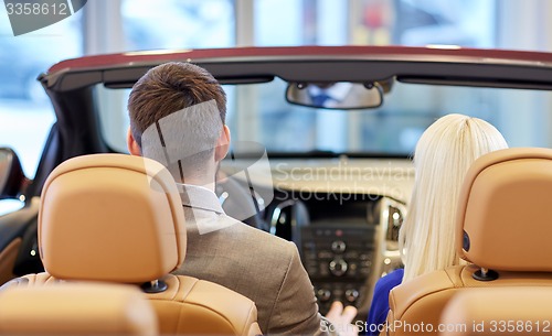 Image of couple sitting in cabriolet car at auto show