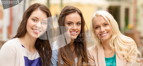Image of three beautiful girls drinking coffee in cafe