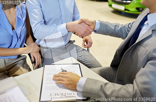 Image of handshake of customer and car dealer in auto salon