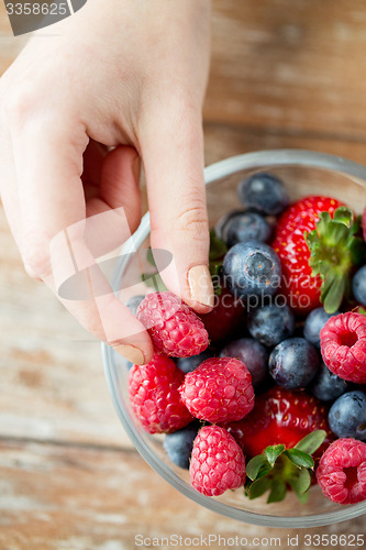 Image of close up of woman hands with berries in glass bowl