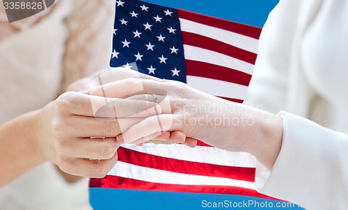 Image of close up of lesbian couple hands with wedding ring