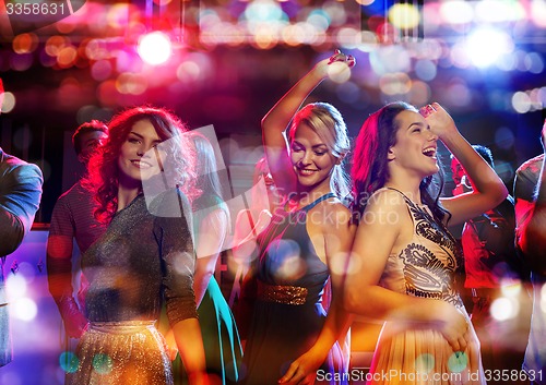 Image of happy friends dancing in club with holidays lights