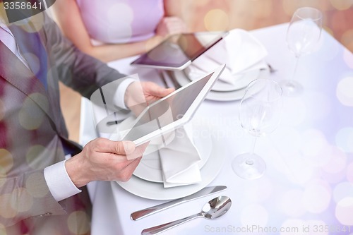Image of close up of couple with tablet pc at restaurant
