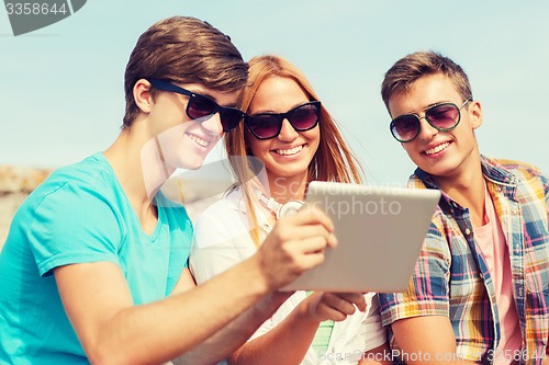 Image of group of smiling friends with tablet pc outdoors