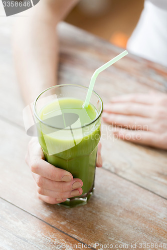 Image of close up of woman hands with green juice