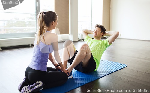 Image of woman with personal trainer doing sit ups in gym