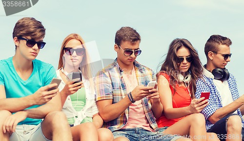 Image of group of friends with smartphones outdoors