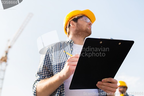 Image of builder in hardhat with clipboard outdoors