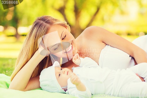 Image of happy mother lying with little baby on blanket