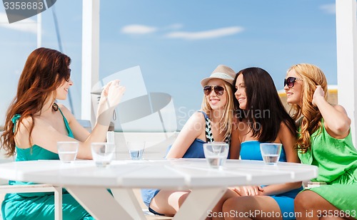 Image of girls taking photo in cafe on the beach