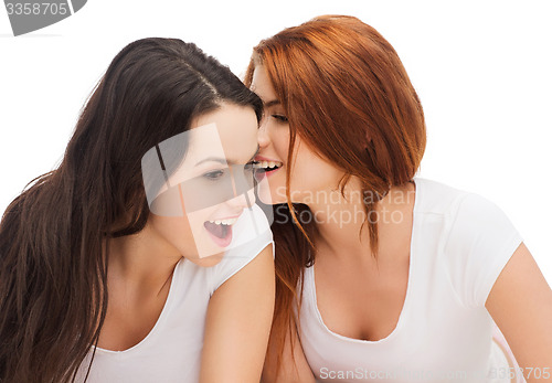 Image of two smiling girls whispering gossip