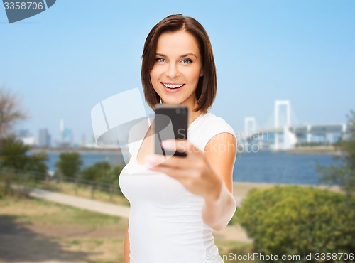 Image of woman taking selfie with smartphone over tokyo