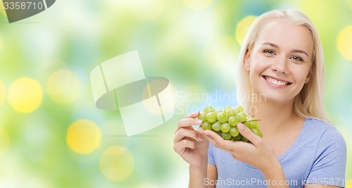 Image of happy woman eating grapes