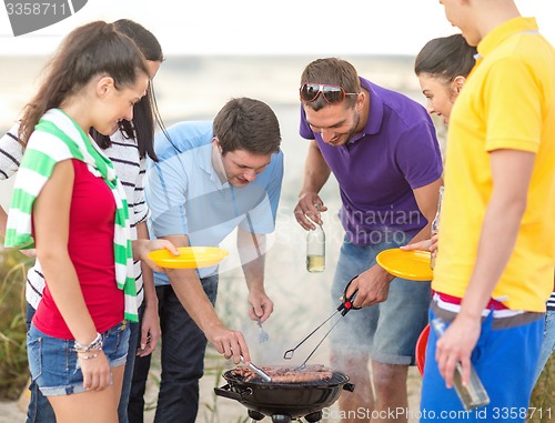 Image of group of friends having picnic on beach