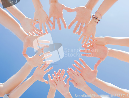 Image of many hands over blue sky background