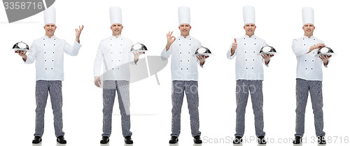 Image of happy male chef cook holding cloche