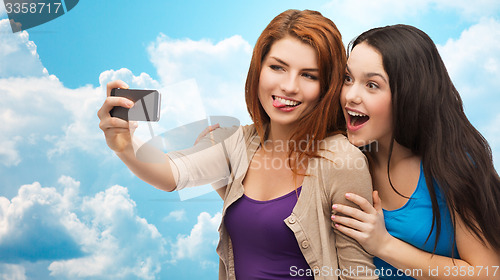 Image of happy teenage girls taking selfie with smartphone